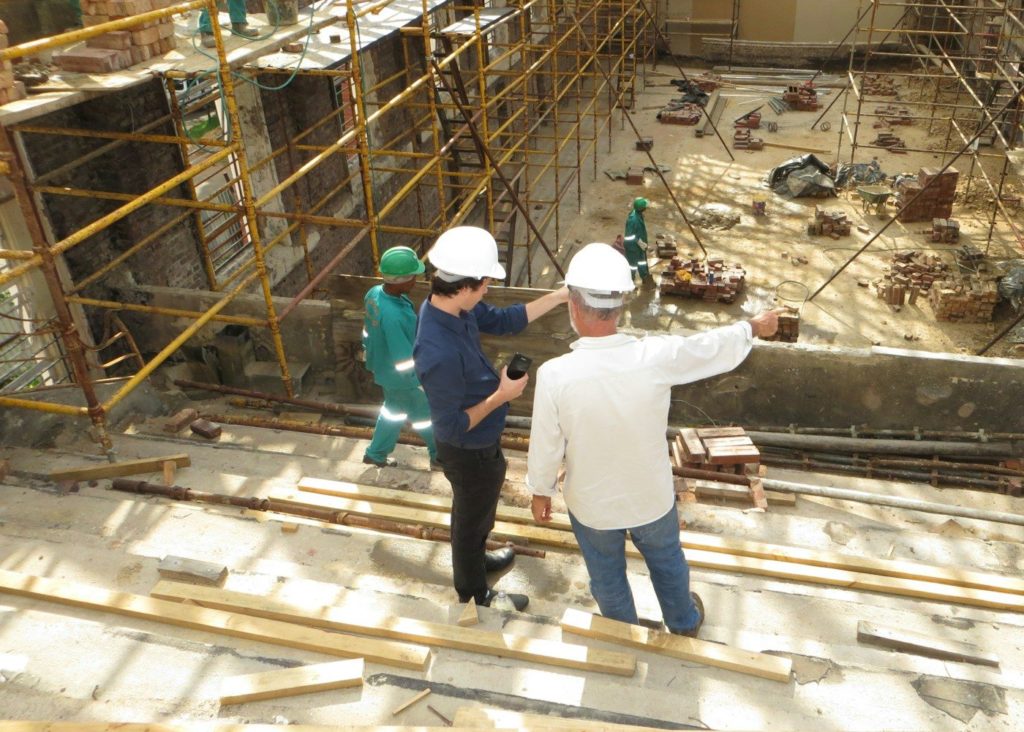 man in white long sleeve shirt and blue denim jeans standing on white metal ladder